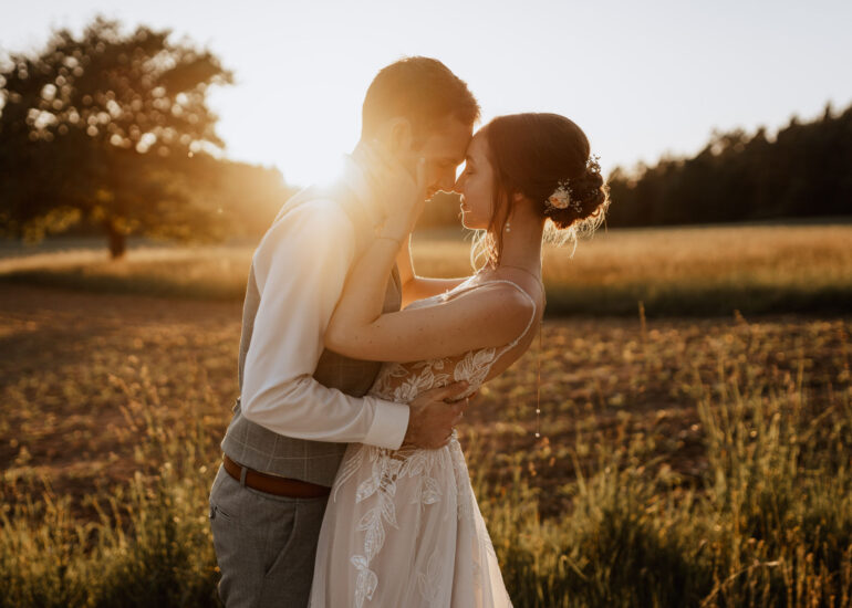Tim und Krissi im goldenen Abendlicht auf einer Wiese, Hochzeit in Bayern